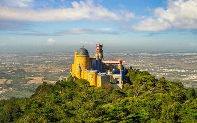 Pena Palace in Sintra, Portugal, surrounded by lush greenery with a panoramic view.