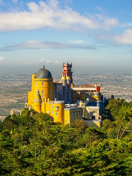 Pena Palace in Sintra, Portugal, surrounded by lush greenery with a panoramic view.