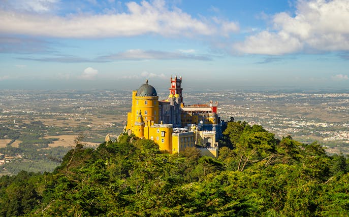 Pena Palace in Sintra, Portugal, surrounded by lush greenery with a panoramic view.
