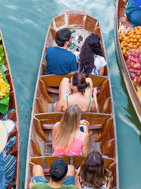 Boats with tourists and vendors selling fruit at Damnoen Saduak Floating Market, Thailand.