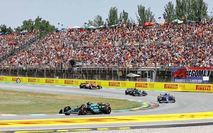 Formula 1 cars racing on Circuit de Barcelona-Catalunya with a packed grandstand.
