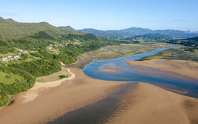 Aerial view of Mundaka estuary with lush greenery and winding river near Bilbao.