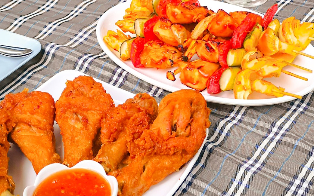 Grilled skewers and fried chicken on a lunch platter aboard a luxury tail boat in Krabi.