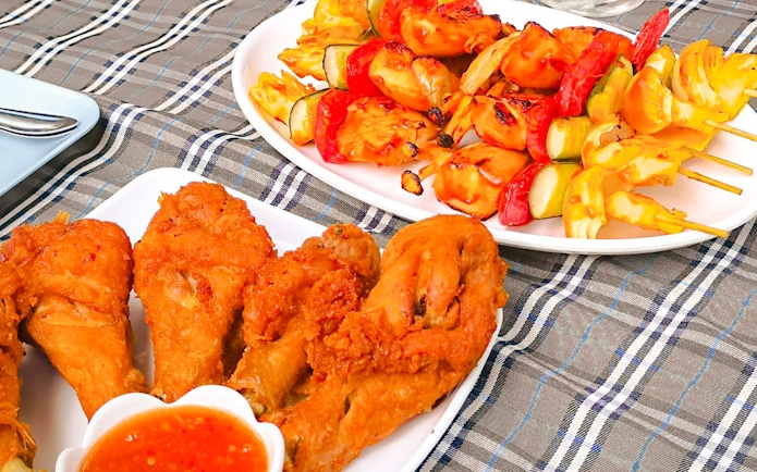 Grilled skewers and fried chicken on a lunch platter aboard a luxury tail boat in Krabi.