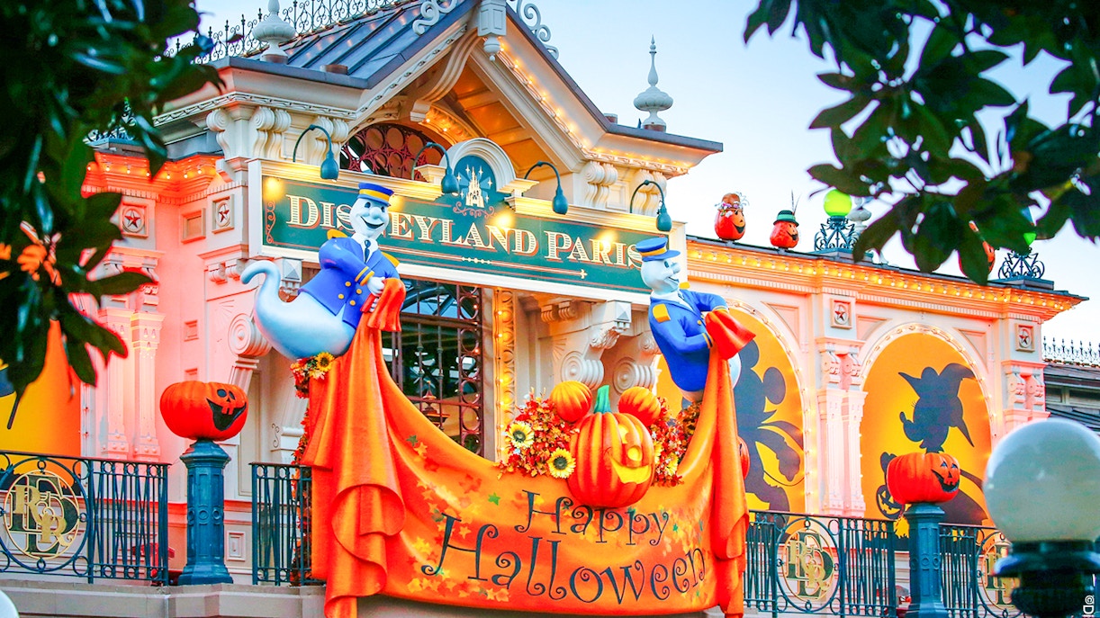 Disneyland Paris entrance decorated for Halloween with pumpkins and ghost figures.