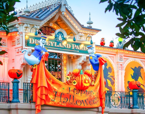 Disneyland Paris entrance decorated for Halloween with pumpkins and ghost figures.