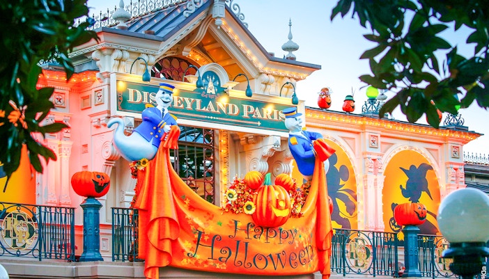 Disneyland Paris entrance decorated for Halloween with pumpkins and ghost figures.