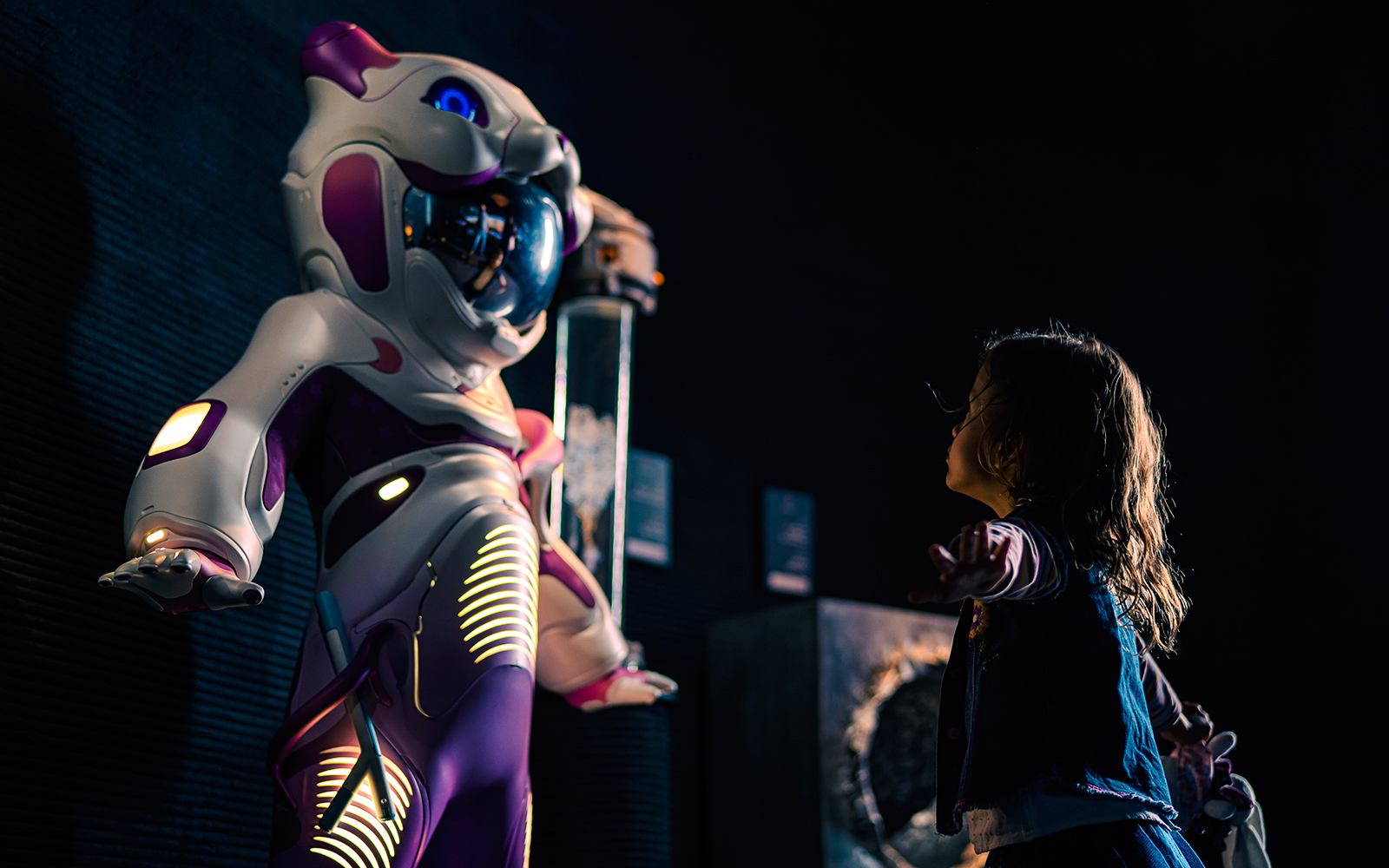 Child interacting with futuristic robot at Museum of the Future exhibit.