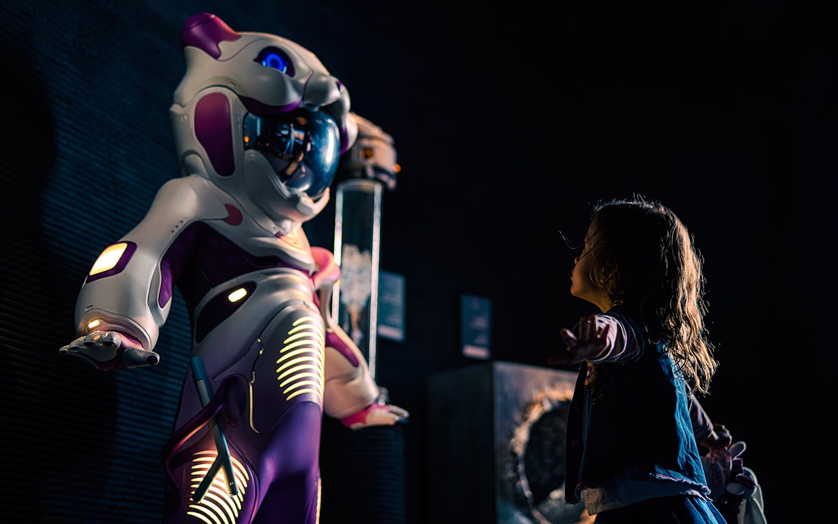 Child interacting with futuristic robot at Museum of the Future exhibit.