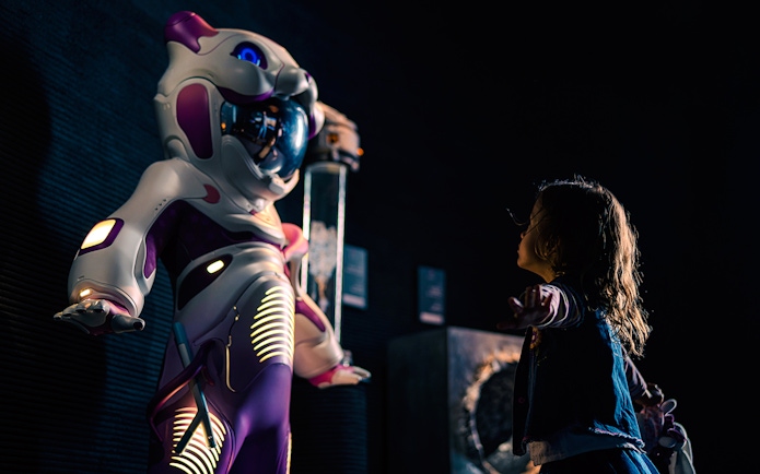 Child interacting with futuristic robot at Museum of the Future exhibit.