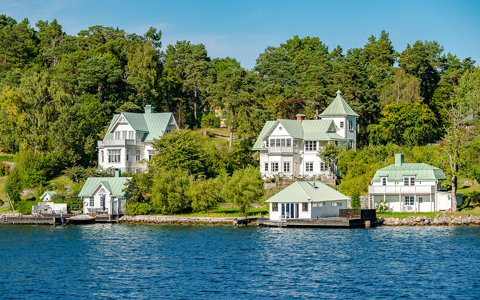Stockholm waterfront houses with green roofs surrounded by trees and water.