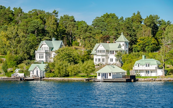 Stockholm waterfront houses with green roofs surrounded by trees and water.