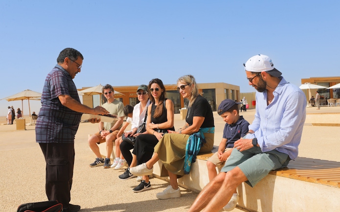 Tourists listening to a guide at Giza Pyramids and the Sphinx, Egypt.