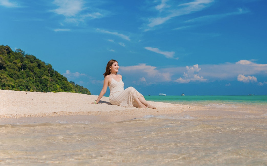 Tourist relaxing on sandy beach at Chong Khad Bay with clear blue sky.