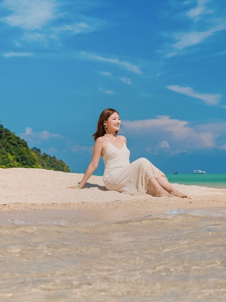 Tourist relaxing on sandy beach at Chong Khad Bay with clear blue sky.