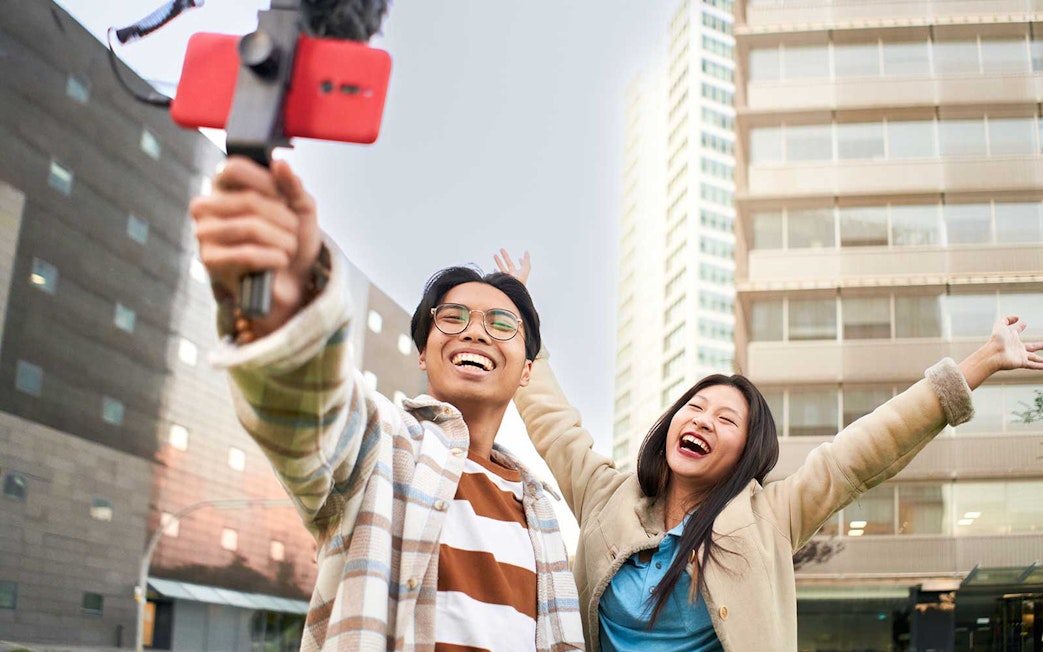 Couple taking a selfie in Singapore with city buildings in the background.