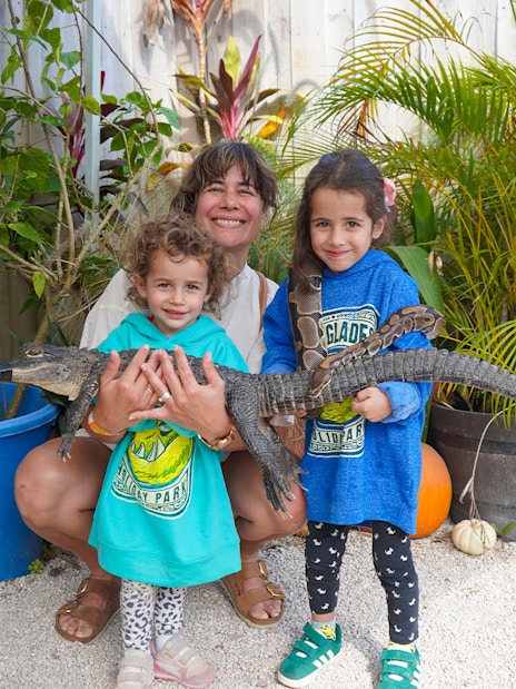 Family holding a small alligator at Holiday Park animal encounter.