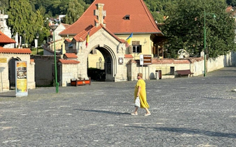 Courtyard entrance in Schei, Brașov with Romanian flags and cobblestone street.