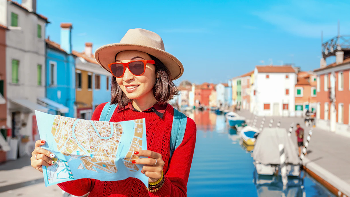 Visitor with map exploring colorful Burano Island canal.