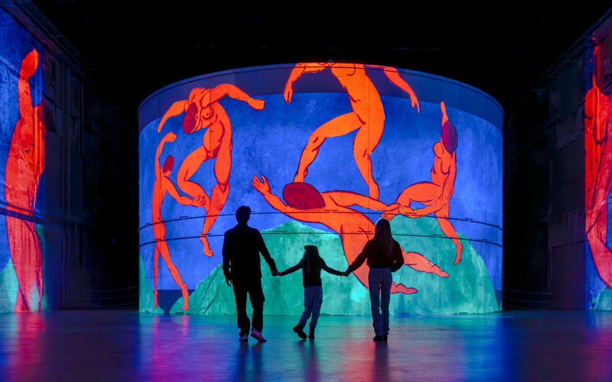 Family viewing Matisse's "Symphony of Colors" at Bassins des Lumières exhibition.