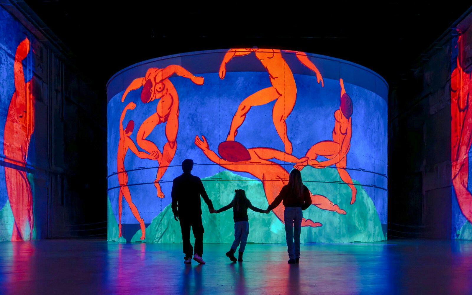 Family viewing Matisse's "Symphony of Colors" at Bassins des Lumières exhibition.