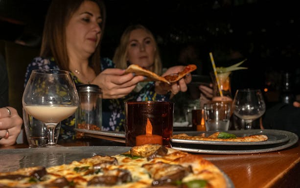 Guests enjoying pizza and cocktails during a guided tour of Melbourne's hidden bars.