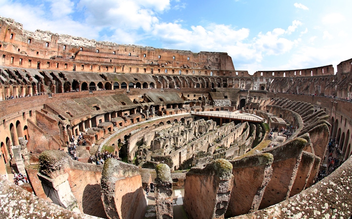 Colosseum interior view with ancient stone arches and arena floor in Rome, Italy.