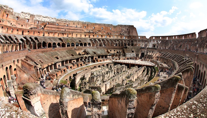Colosseum interior view with ancient stone arches and arena floor in Rome, Italy.
