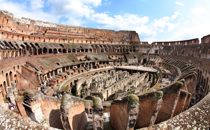 Colosseum interior view with ancient stone arches and arena floor in Rome, Italy.