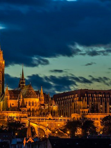 Budapest skyline with illuminated Matthias Church at dusk during Danube cruise.