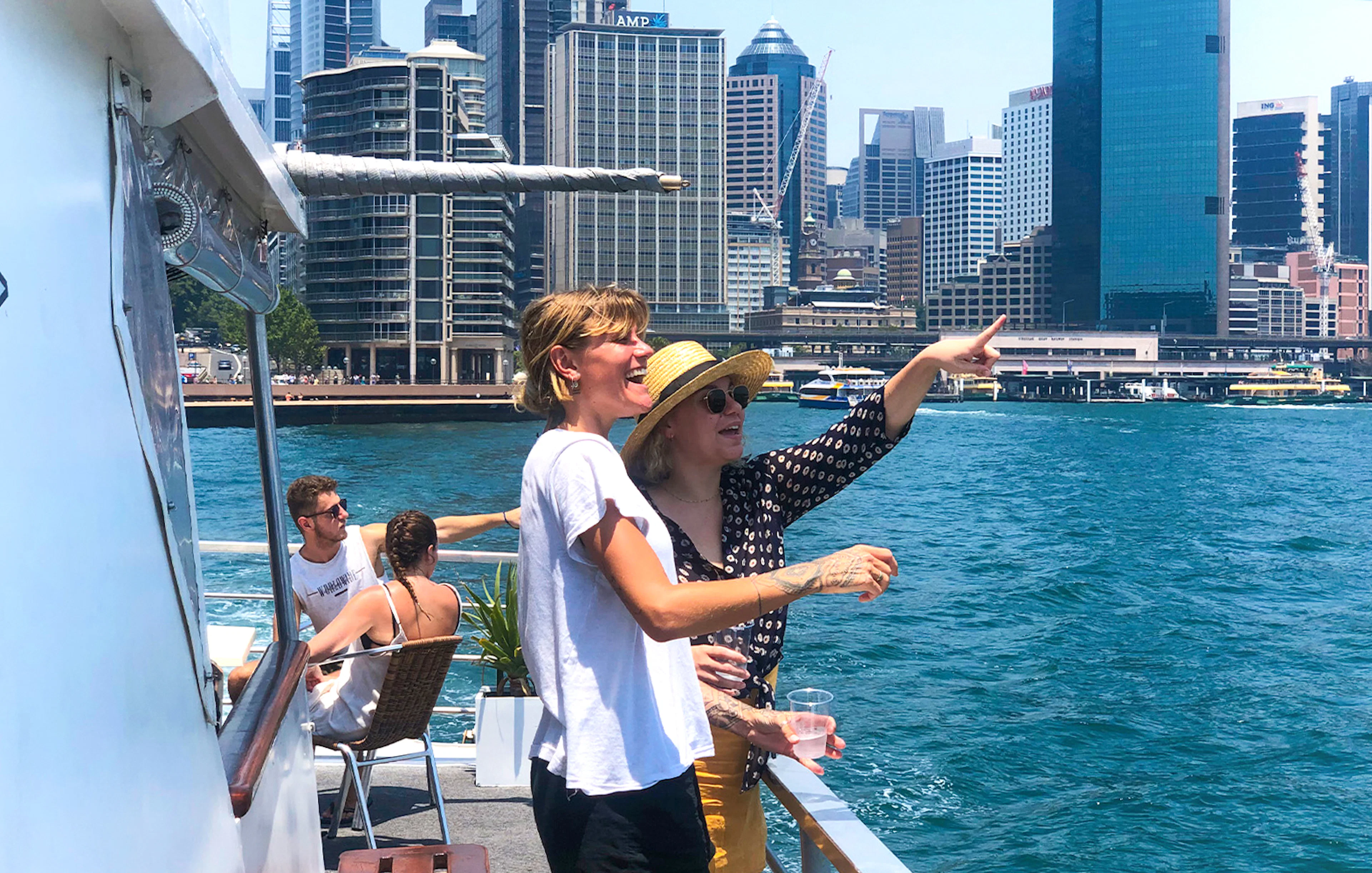 Tourists enjoying a Sydney Harbour sightseeing cruise with city skyline views.