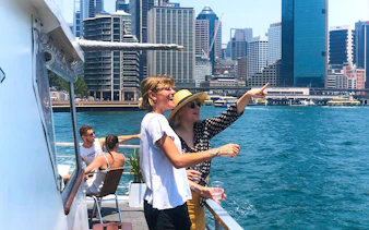 Tourists enjoying a Sydney Harbour sightseeing cruise with city skyline views.