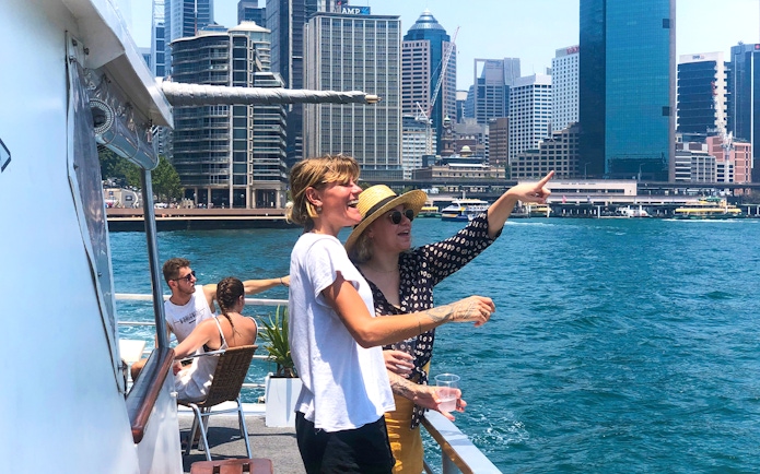 Tourists enjoying a Sydney Harbour sightseeing cruise with city skyline views.