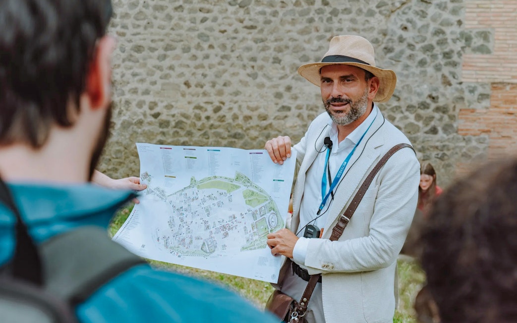 Tour guide in Pompeii holding a map and briefing tourists.