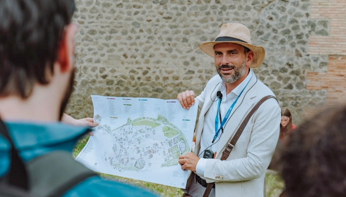 Tour guide in Pompeii holding a map and briefing tourists.
