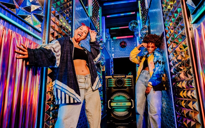 Visitors enjoying vibrant room at Upside Down Amsterdam with colorful lights and decor.