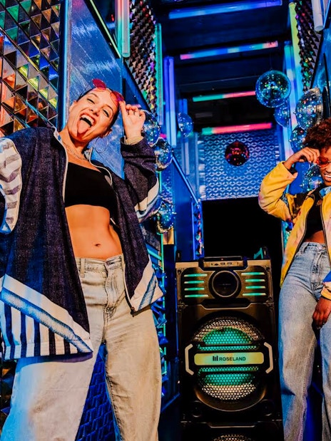 Visitors enjoying vibrant room at Upside Down Amsterdam with colorful lights and decor.