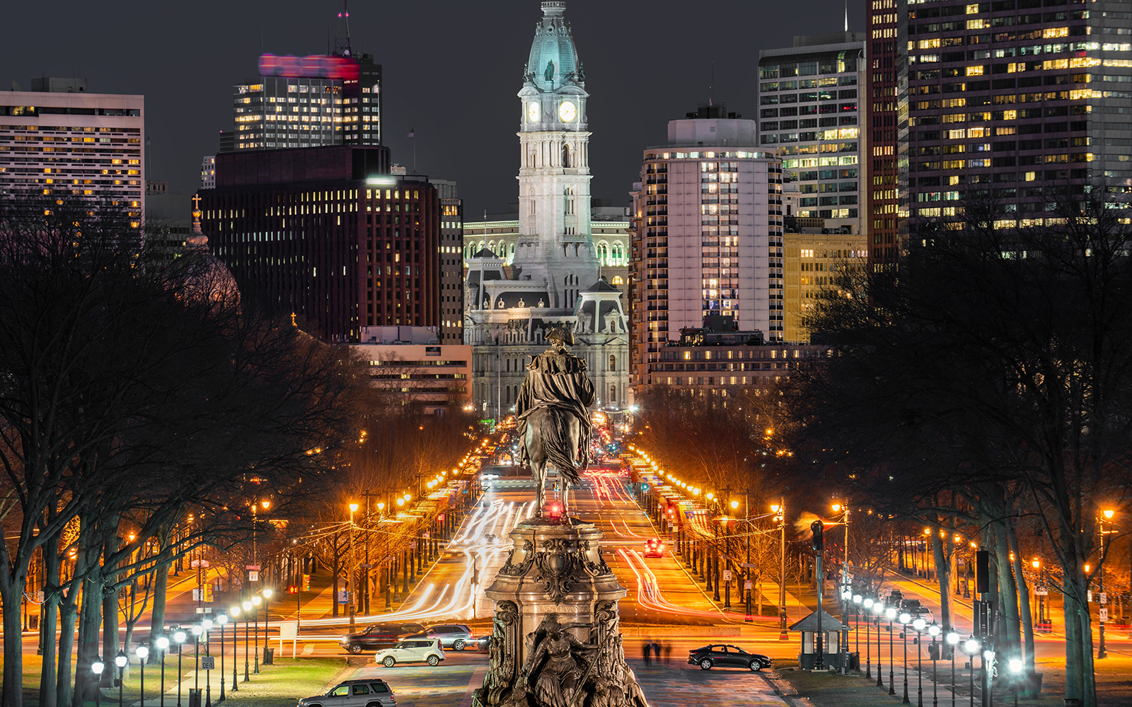 Philadelphia City Hall illuminated at night with traffic lights on Benjamin Franklin Parkway.