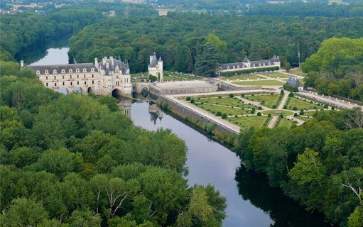 Aerial view of Château de Chenonceau spanning the Cher River in Loire Valley, France.