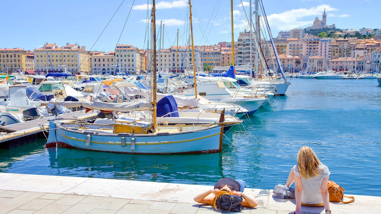 Boats docked at Marseille's Vieux Port with Notre-Dame de la Garde in the background.