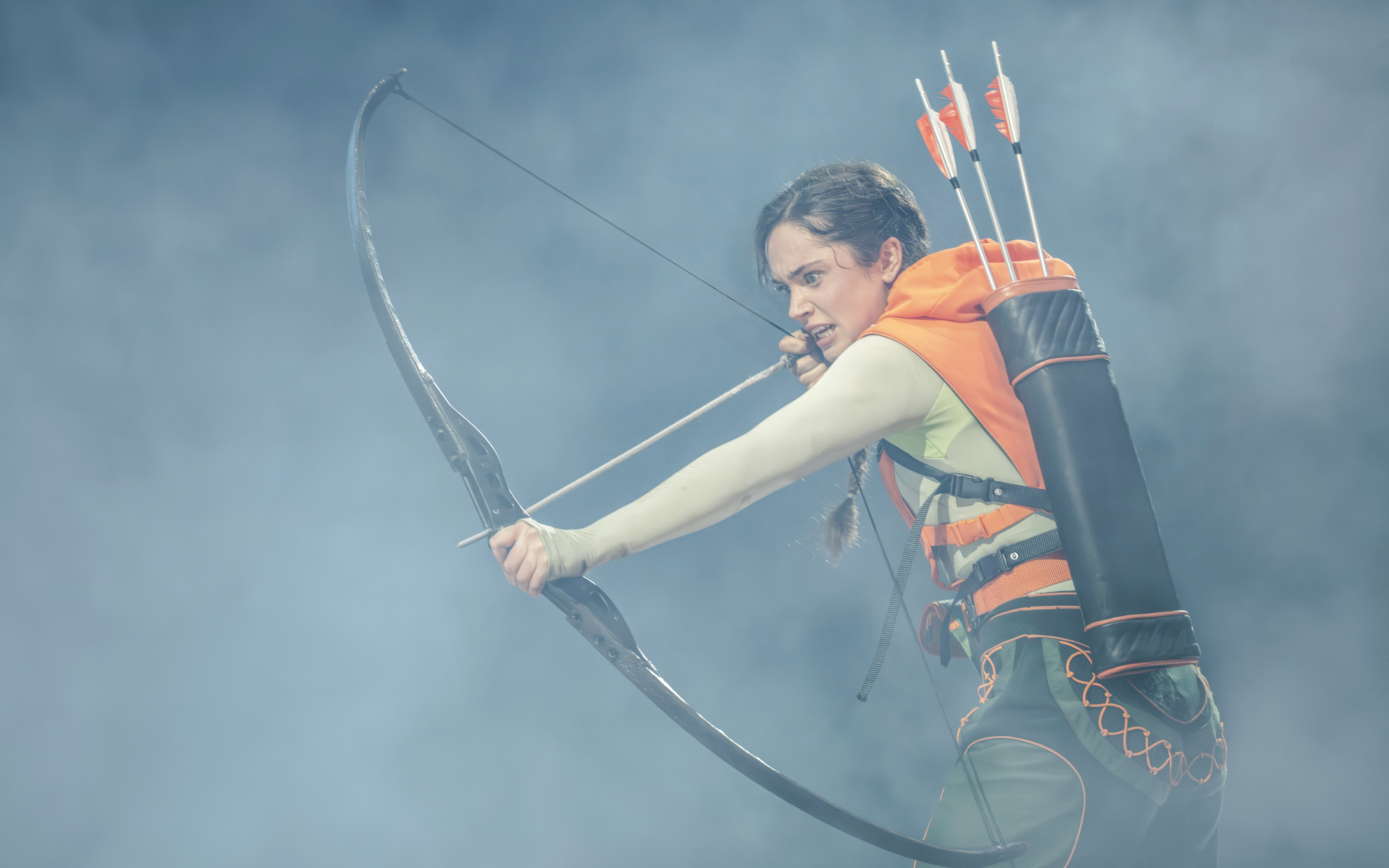 Performer with bow and arrows in Hunger Games West End show.