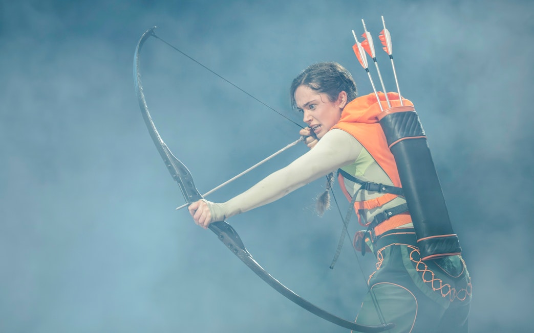 Performer with bow and arrows in Hunger Games West End show.