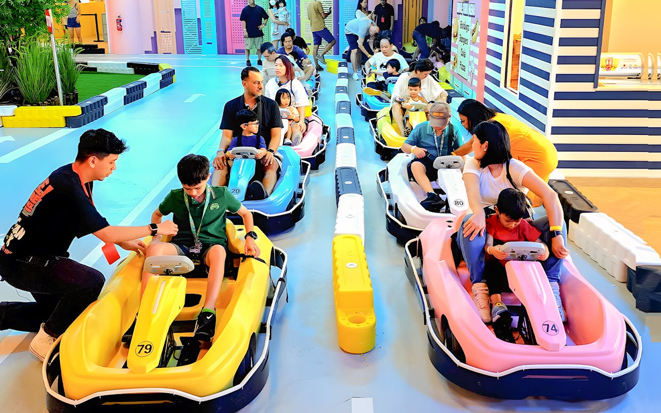 Families and children prepare to ride colorful go-karts at VroomTown Driving City.