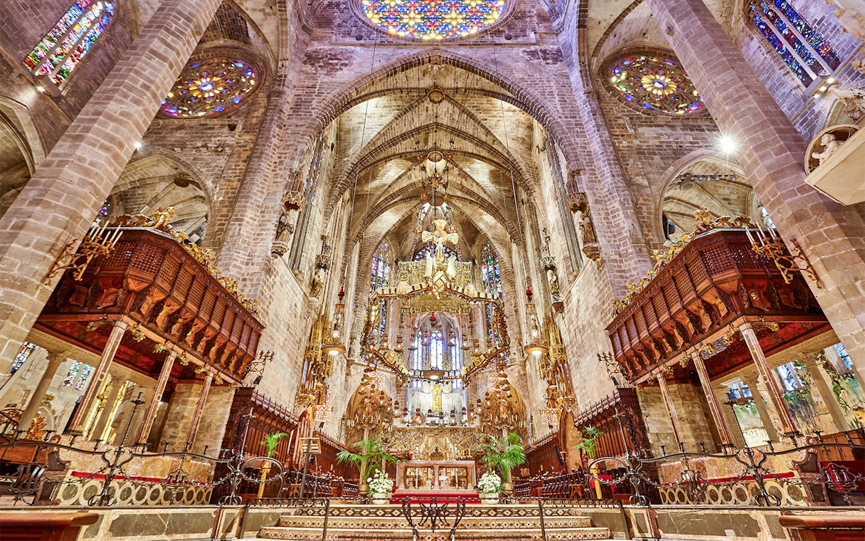 Palma Cathedral interior with ornate altar and stained glass windows.