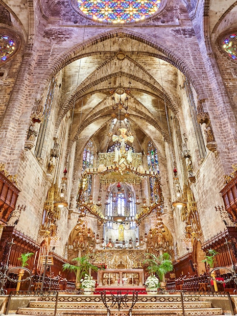 Palma Cathedral interior with ornate altar and stained glass windows.