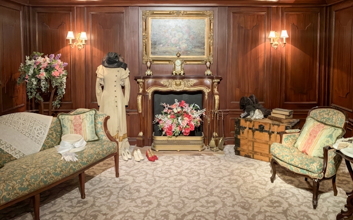 Titanic first-class cabin replica with period furniture and clothing display.