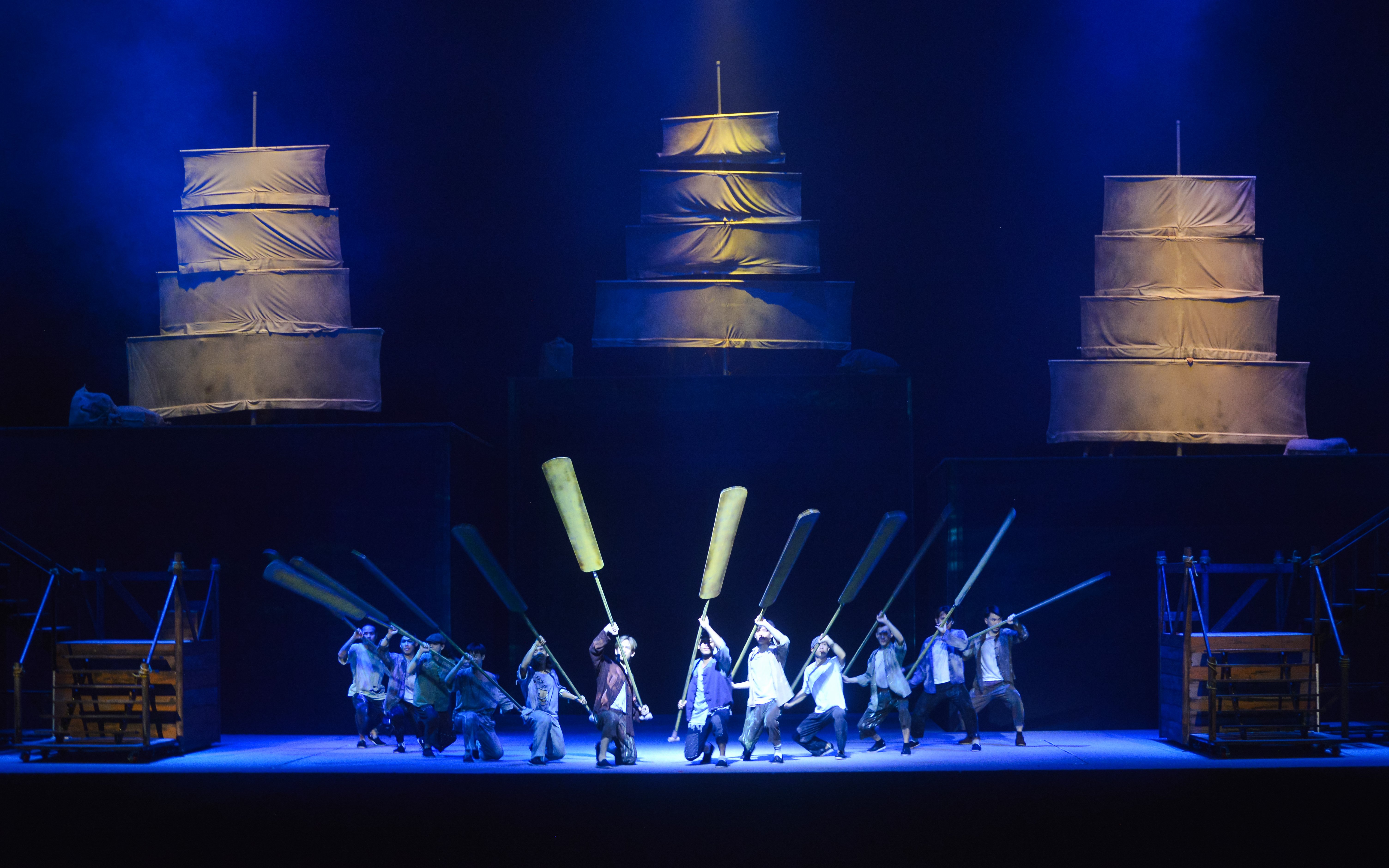 Performers with oars on stage at Encore Melaka cultural show in Malaysia.