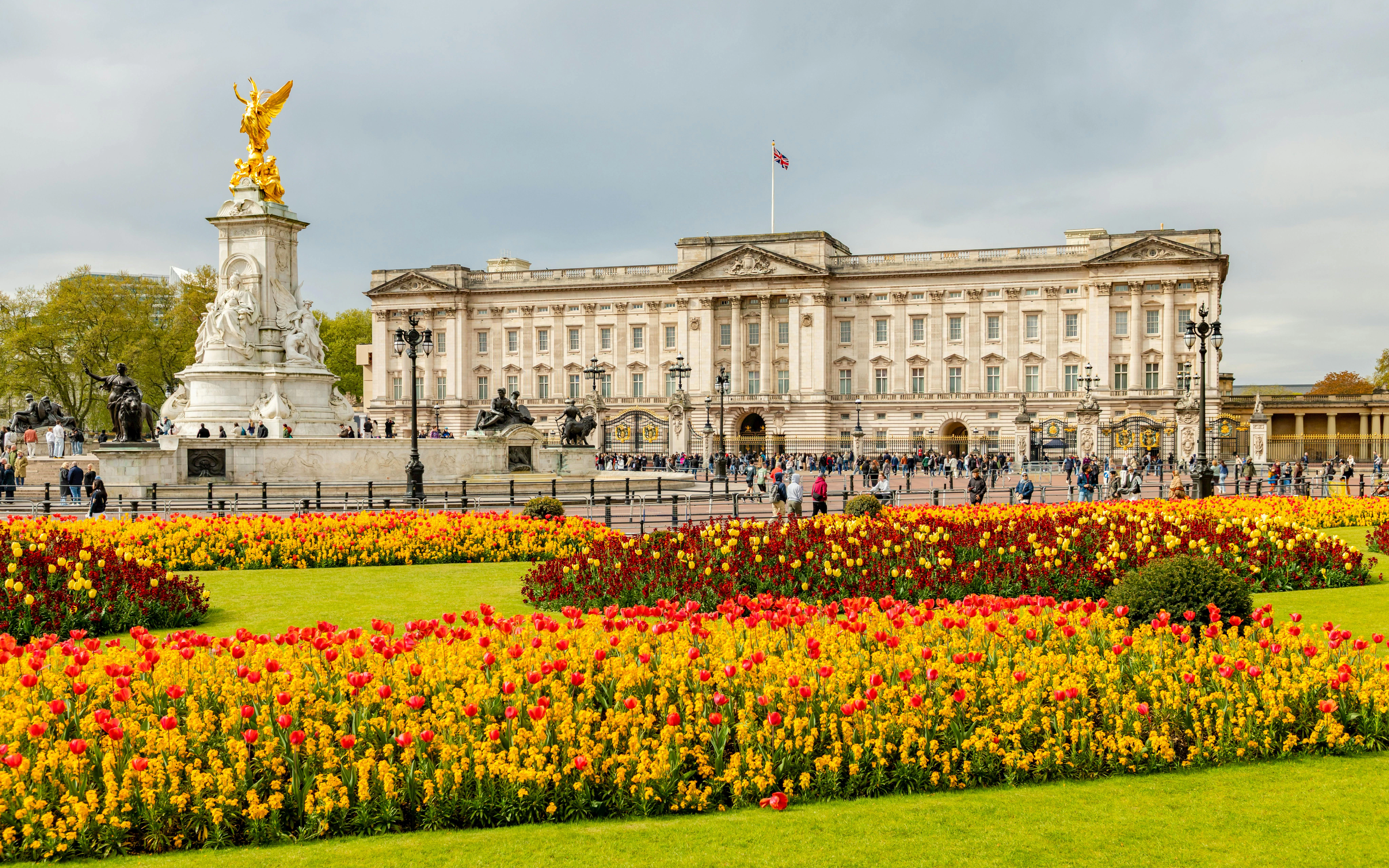 Buckingham Palace with Queen Victoria Memorial and colorful gardens in London.