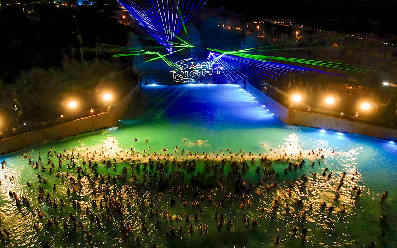 Siam Park illuminated at night with vibrant water slides and palm trees in Tenerife, Spain.