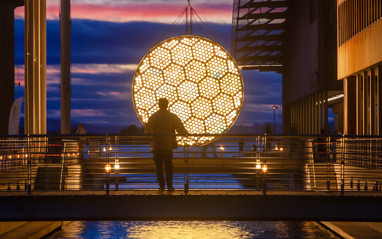 Man viewing illuminated art installation during Amsterdam Light Festival cruise.